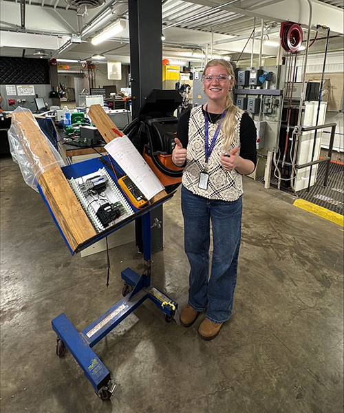 woman on manufacturing floor next to equipment