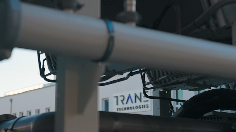 Industrial pipes with Trane Technologies logo shown in background on exterior building