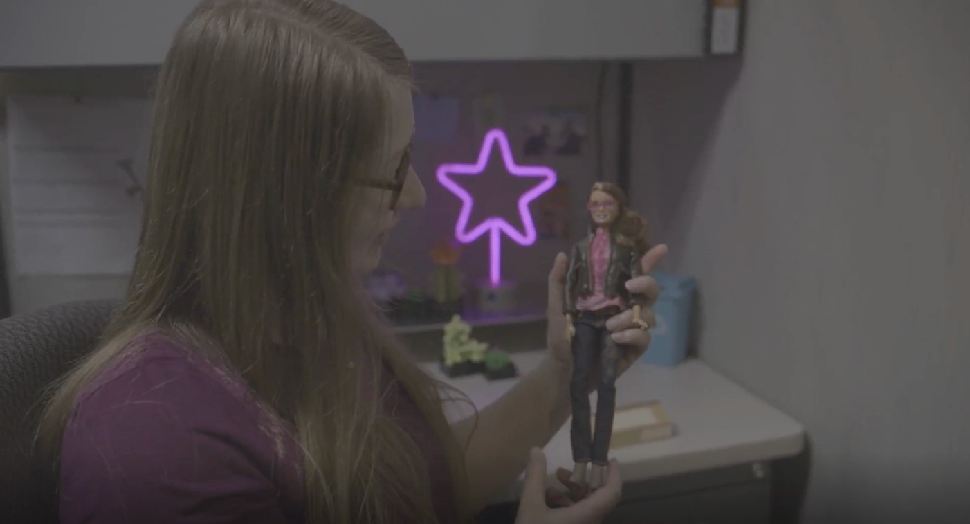 Rebecca holding an action figure of herself